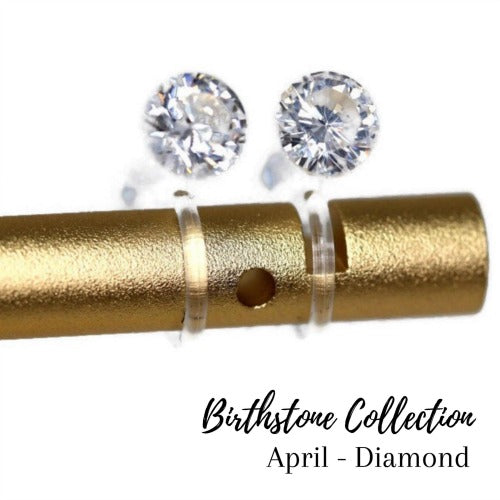 A pair of clear cubic zirconia stud earrings mounted on a gold-colored post, part of the Birthstone Collection for April.