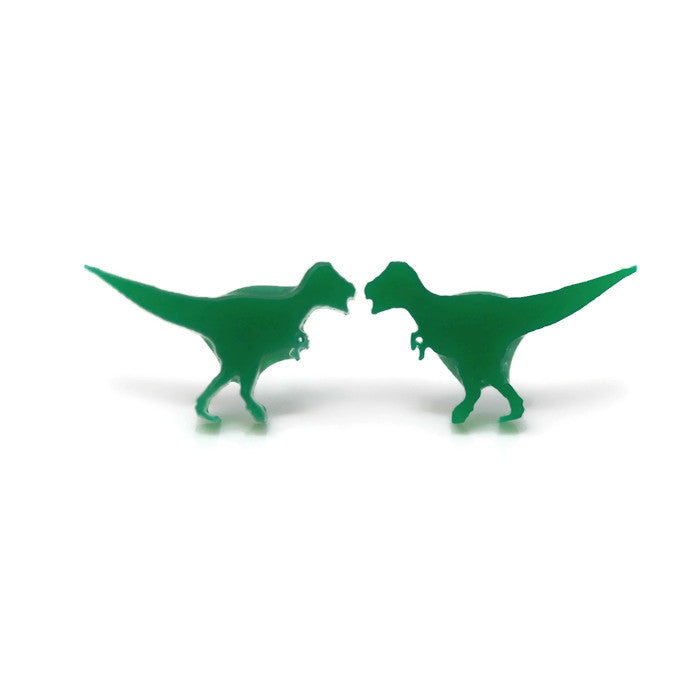 A pair of green acrylic T-Rex dinosaur stud earrings against a white background.