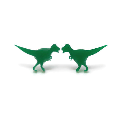 A pair of green acrylic T-Rex dinosaur stud earrings against a white background.