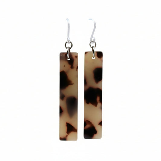 A pair of tortoise shell grey acrylic bar dangle earrings displayed on a white surface.