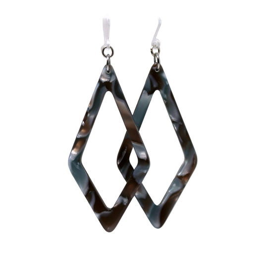 A pair of acrylic dangle earrings with a rhomboid pattern in blue and green shades, displayed on a white surface with a floral background.