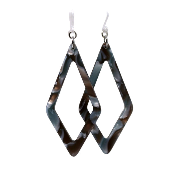 A pair of acrylic dangle earrings with a rhomboid pattern in blue and green shades, displayed on a white surface with a floral background.