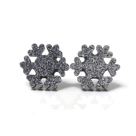 A pair of silver glitter snowflake earrings on plastic posts.