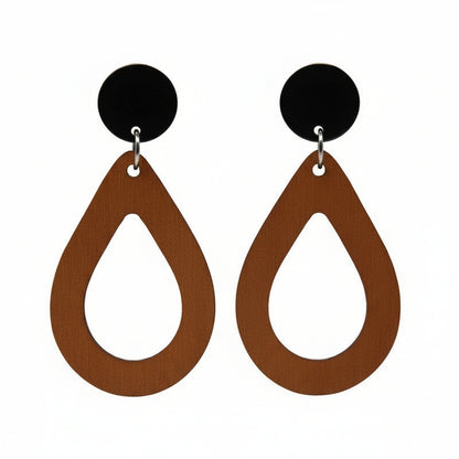 A pair of teardrop dangle earrings with an open design, made of wood attached to black acrylic circles, displayed on a gold-colored metal post.