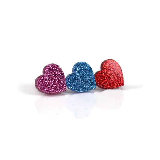 A set of three glittery acrylic heart stud earrings in pink, blue, and red colors, displayed against a white background.