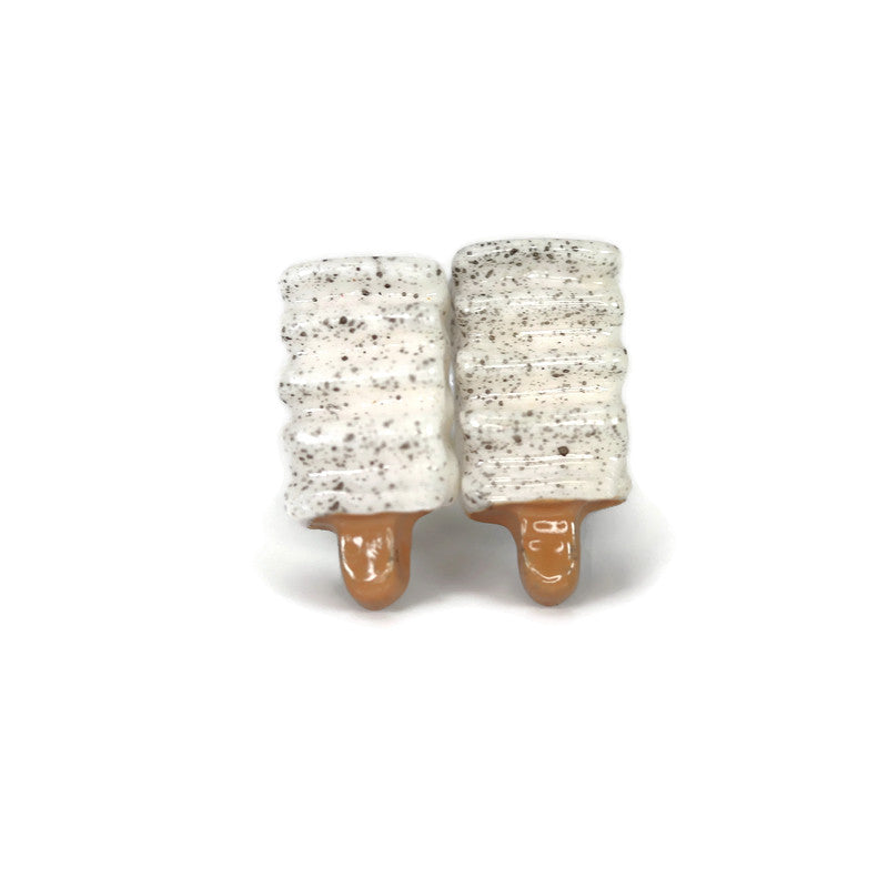 A pair of cookies and cream popsicle-shaped stud earrings with a white and brown speckled design on a white background.