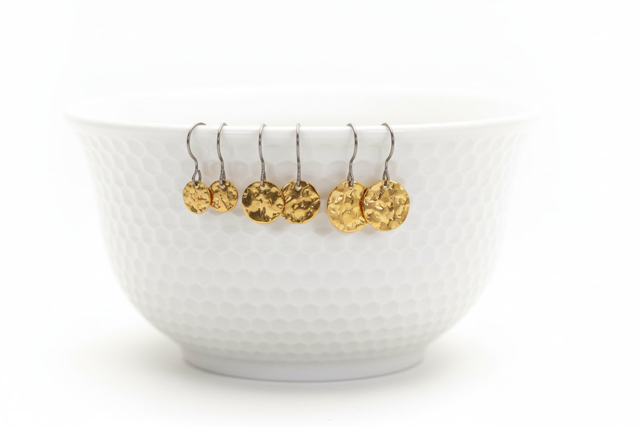 A white bowl with round disk dangle earrings in gold color attached to its edge.