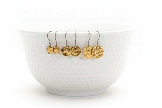 A white bowl with round disk dangle earrings in gold color attached to its edge.