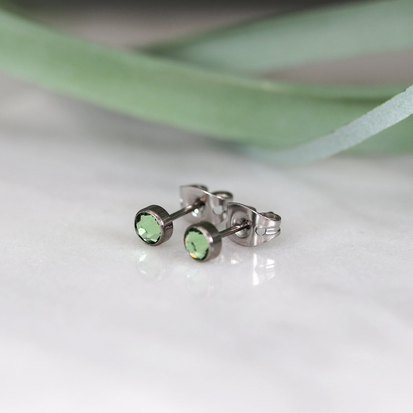 Titanium stud earrings, bezel set crystals, pale green