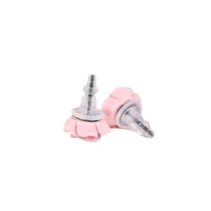 A pair of pink silicone earring backs designed to fit titanium posts, displayed against a floral background.