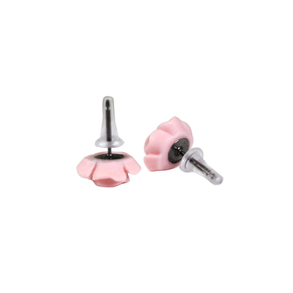 A pair of pink silicone earring backs fitted on a pair of earrings, placed on a white surface with flowers in the background.