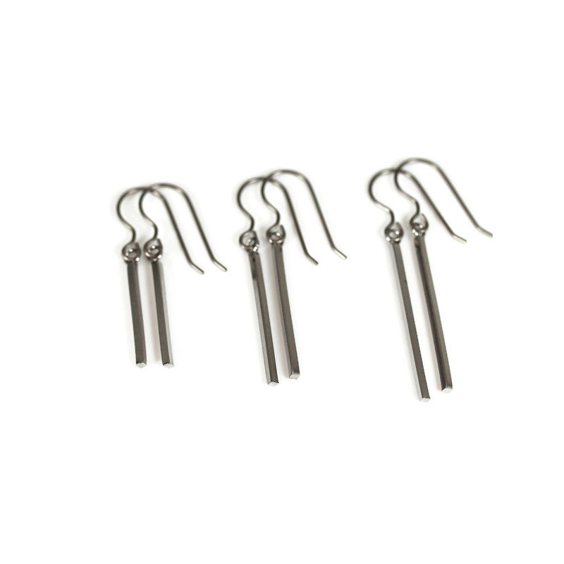 A set of three dangle earrings with bar hooks, made of brushed raw brass, displayed against a white background.