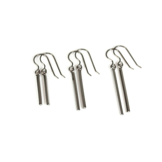 A set of three dangle earrings with bar hooks, made of brushed raw brass, displayed against a white background.