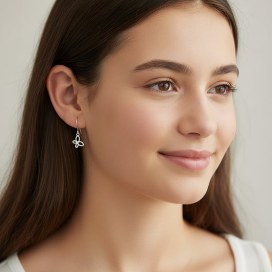Silver butterfly-shaped dangle earrings displayed over a white textured surface.