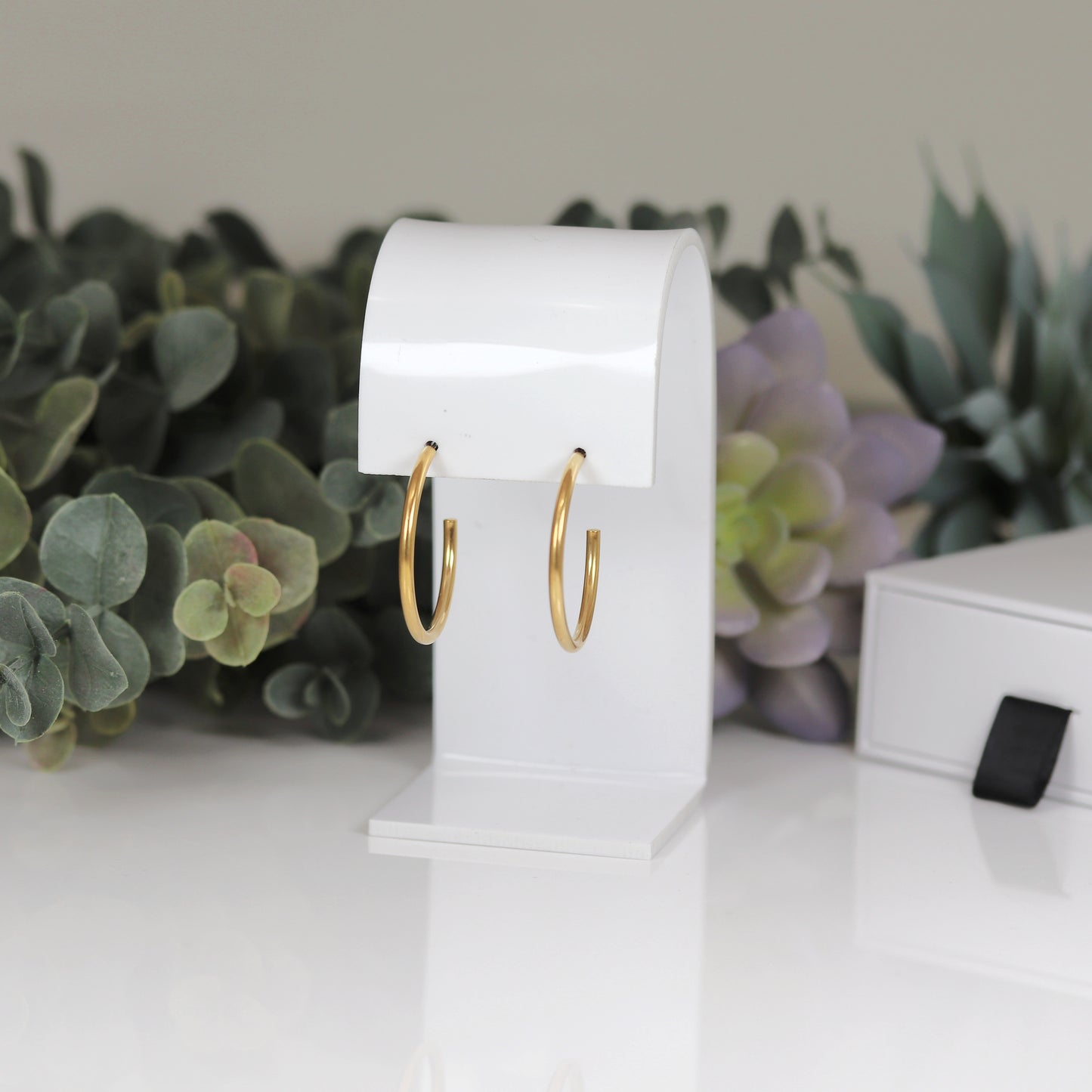 A pair of 30mm hoop stud earrings, one with a gold  finish and the other with a gold plated copper finish.