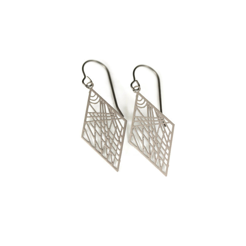 A pair of geometric dainty rhombus dangle earrings in silver color, displayed over a white textured surface.