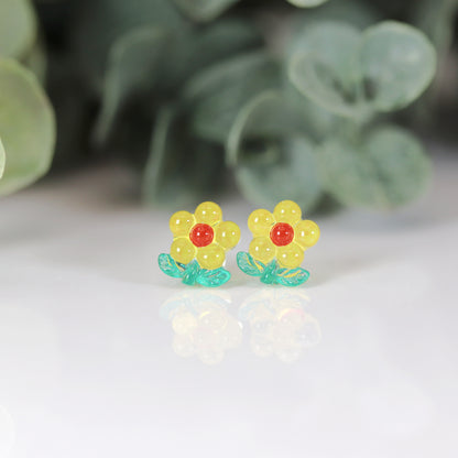 A set of colorful flower stem stud earrings displayed in a row, with colors including pink, blue, green, and yellow.