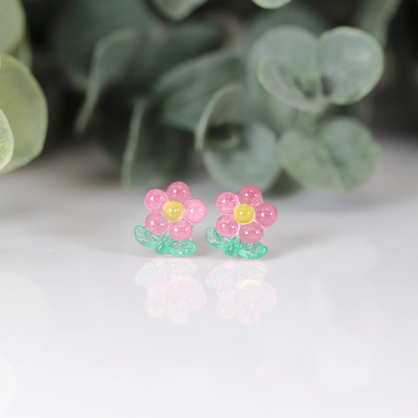 A set of colorful flower stem stud earrings displayed in a row, with colors including pink, blue, green, and yellow.