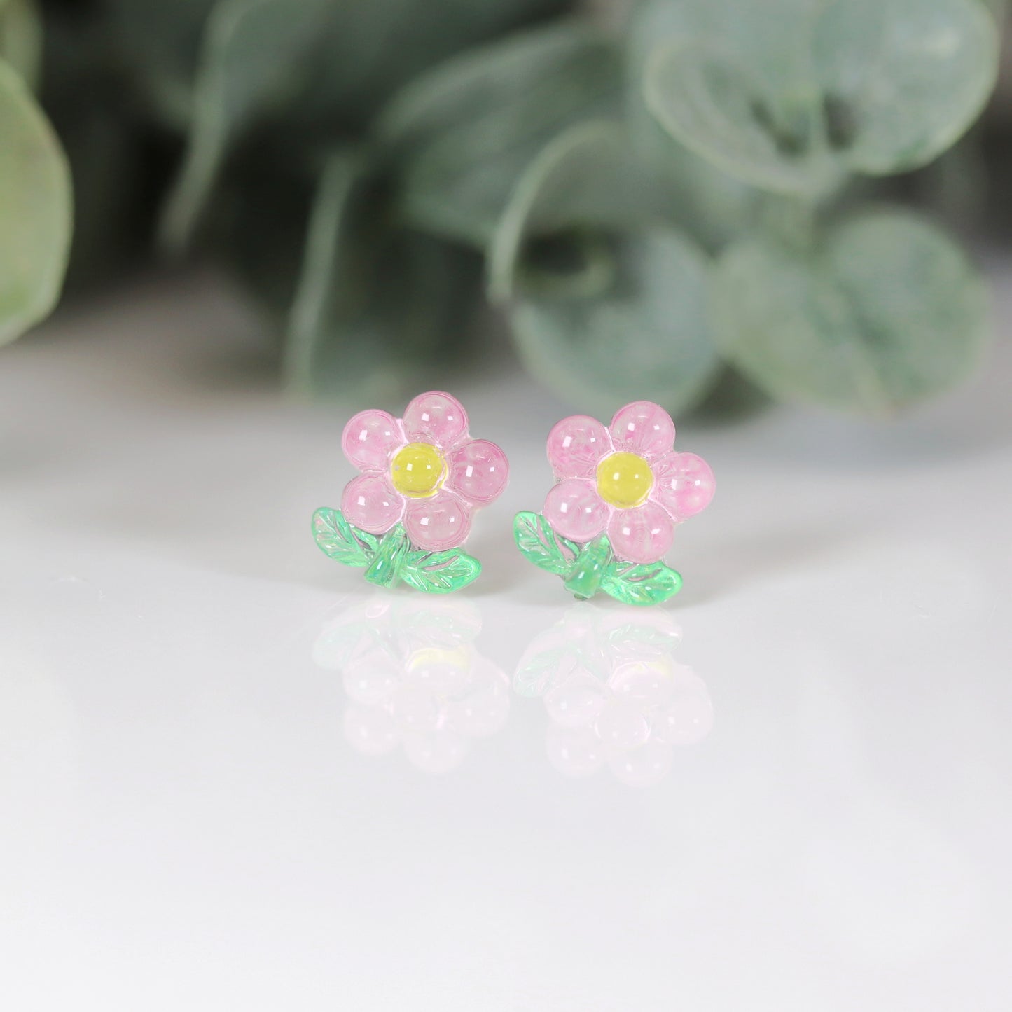 A set of colorful flower stem stud earrings displayed in a row, with colors including pink, blue, green, and yellow.