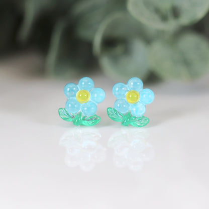 A set of colorful flower stem stud earrings displayed in a row, with colors including pink, blue, green, and yellow.