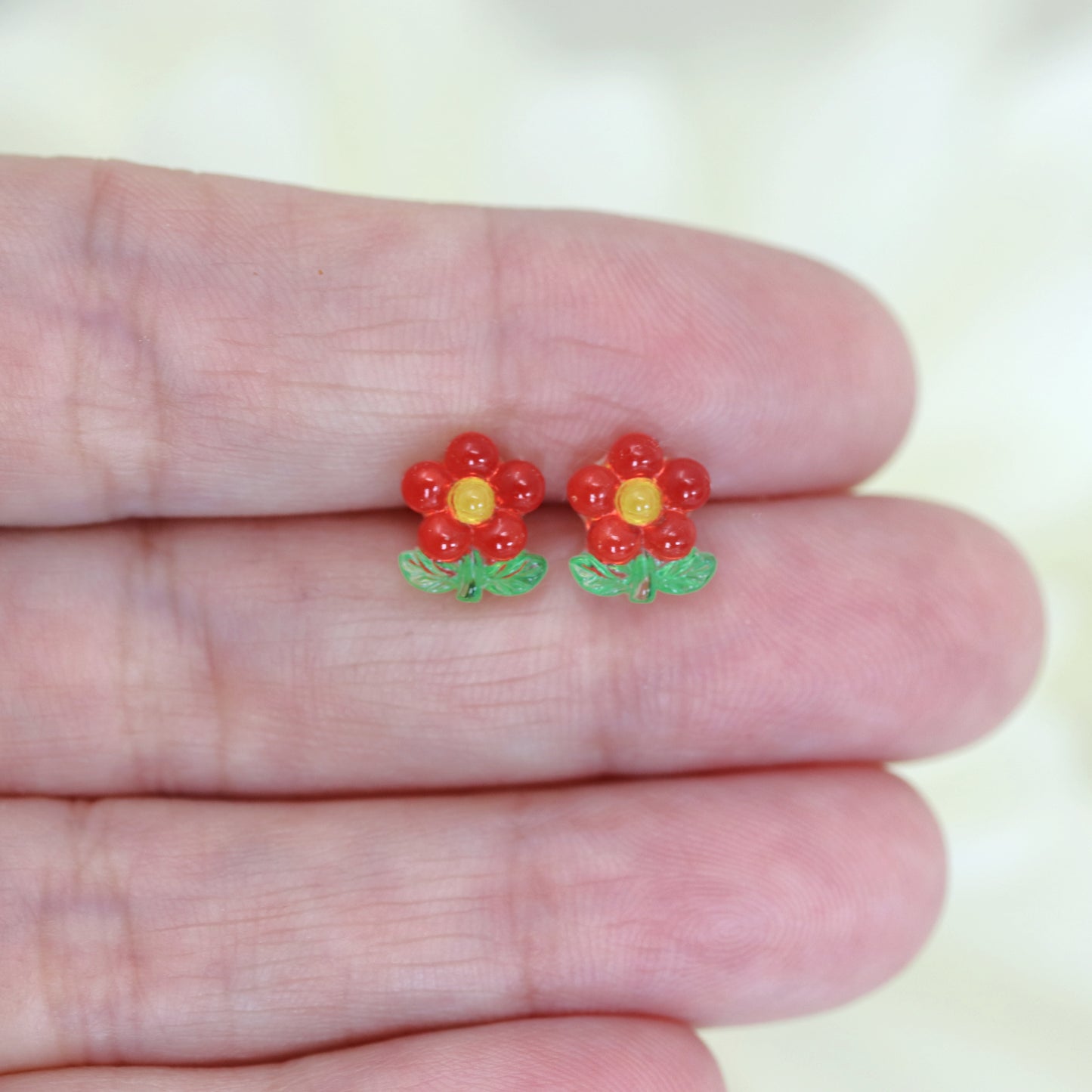 A set of colorful flower stem stud earrings displayed in a row, with colors including pink, blue, green, and yellow.