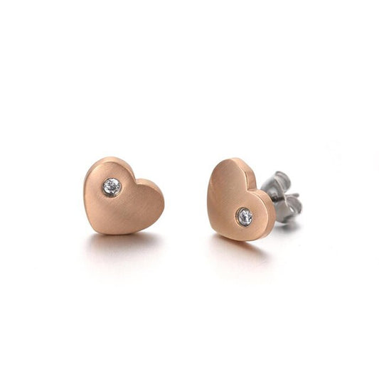 A pair of rose gold titanium heart stud earrings with cubic zirconia, displayed with butterfly and rubber ear nuts.