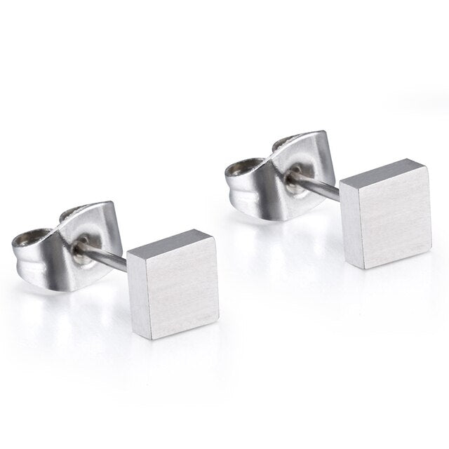A pair of silver titanium square stud earrings laid on a white surface.