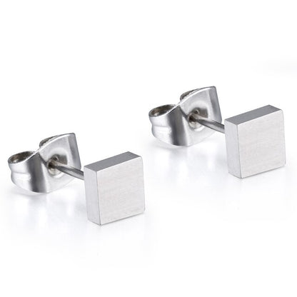 A pair of silver titanium square stud earrings laid on a white surface.