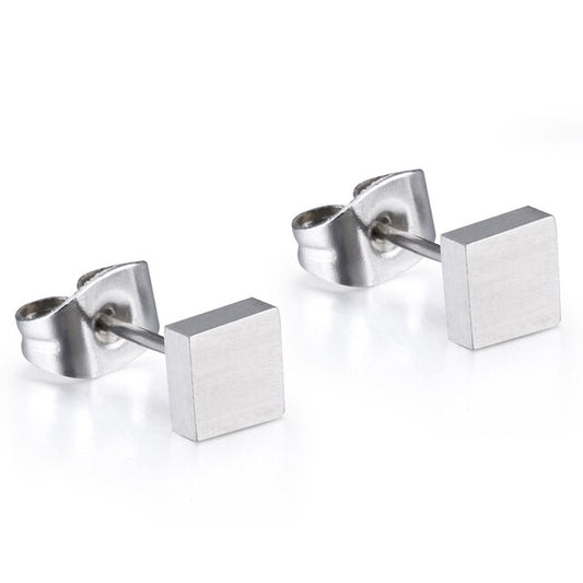A pair of silver titanium square stud earrings laid on a white surface.
