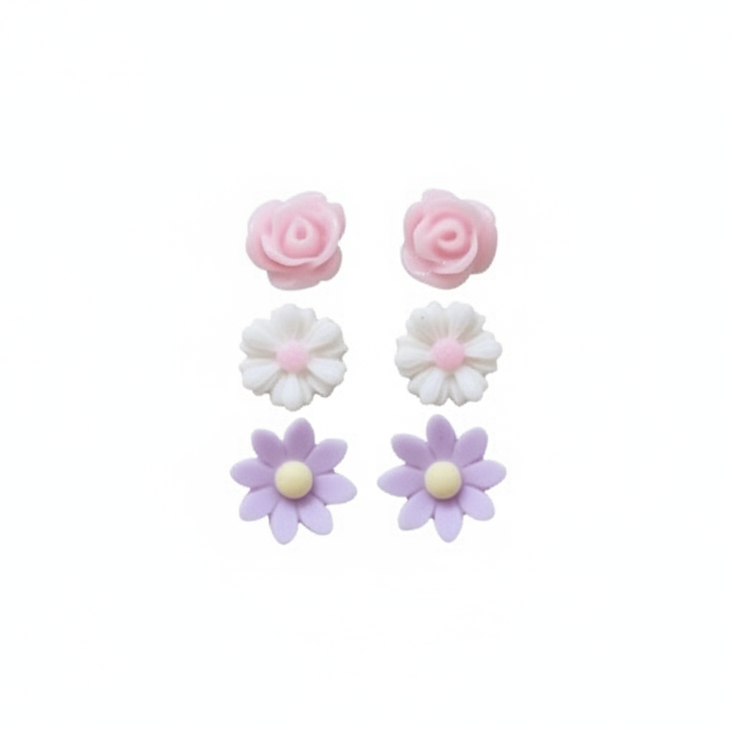 A hand holding three pairs of stud earrings, featuring pink rose, daisy, and wildflower designs in white, pink, and purple colors.