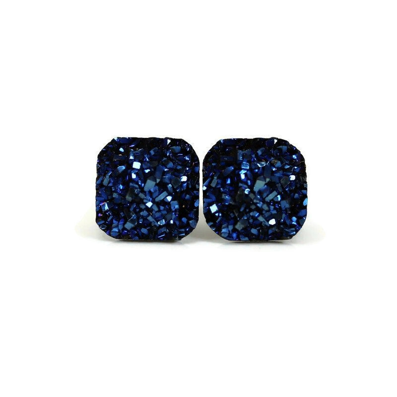 A pair of blue square druzy stud earrings with rounded corners on a white background, with a text overlay saying 'More Colors'.